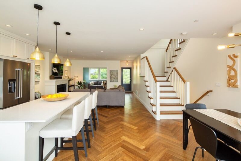Mid-sized transitional l-shaped brown floor and vinyl floor open concept kitchen photo in Vancouver with shaker cabinets, white cabinets, quartz countertops, stainless steel appliances, an island and white countertops