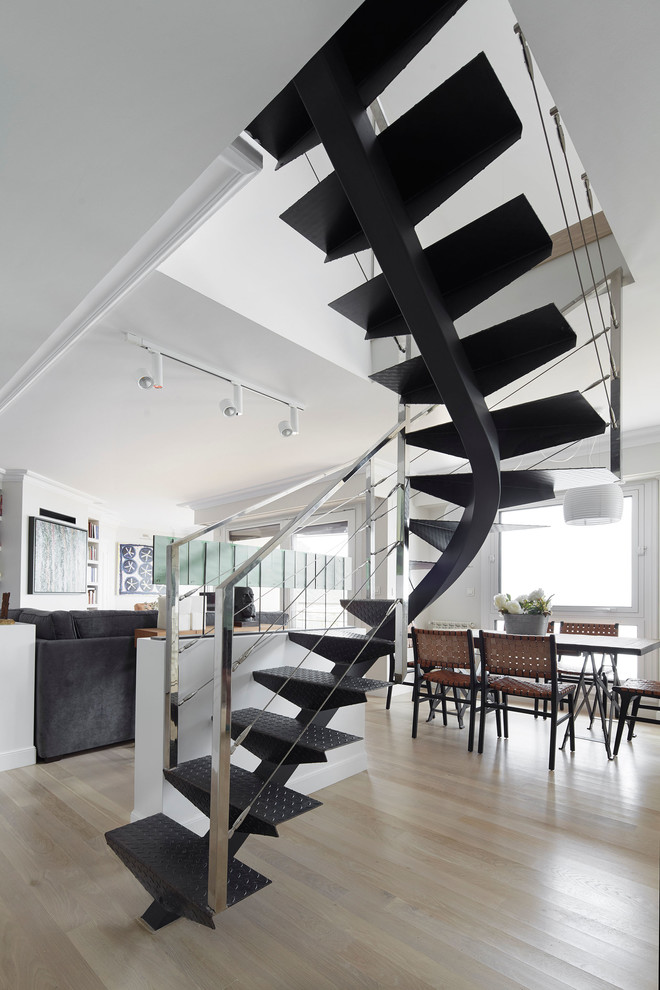 Transitional metal curved staircase in Other with open risers and metal railing.