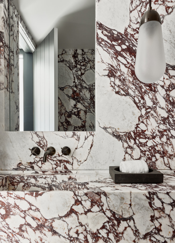 Modern inredning av ett mellanstort flerfärgad flerfärgat badrum, med röda skåp, en vägghängd toalettstol, flerfärgad kakel, marmorkakel, marmorgolv, ett integrerad handfat, marmorbänkskiva och flerfärgat golv