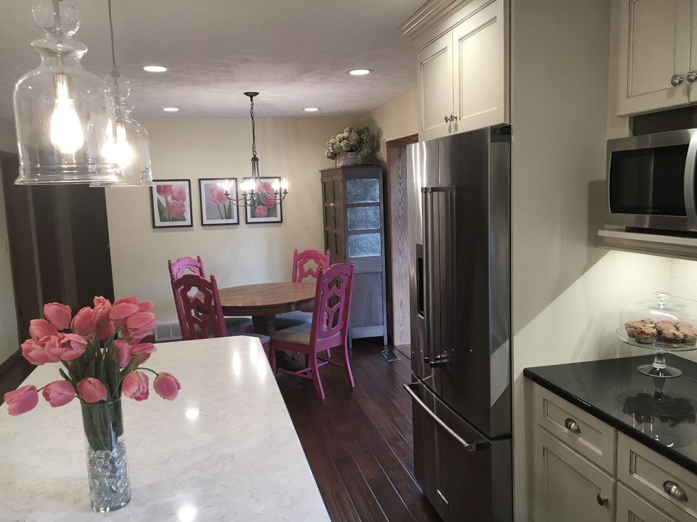 Example of a large transitional medium tone wood floor and brown floor eat-in kitchen design with an undermount sink, flat-panel cabinets, white cabinets, granite countertops, white backsplash, porcelain backsplash, stainless steel appliances and an island