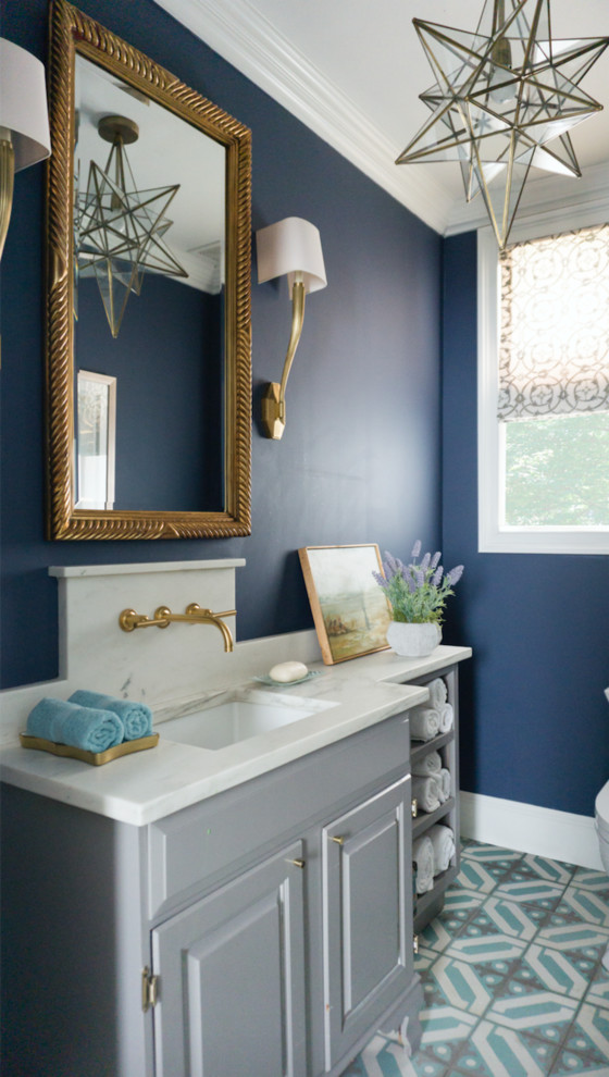 Design ideas for a small eclectic powder room in Chicago with furniture-like cabinets, grey cabinets, a one-piece toilet, blue walls, cement tiles, an undermount sink, marble benchtops, blue floor and white benchtops.