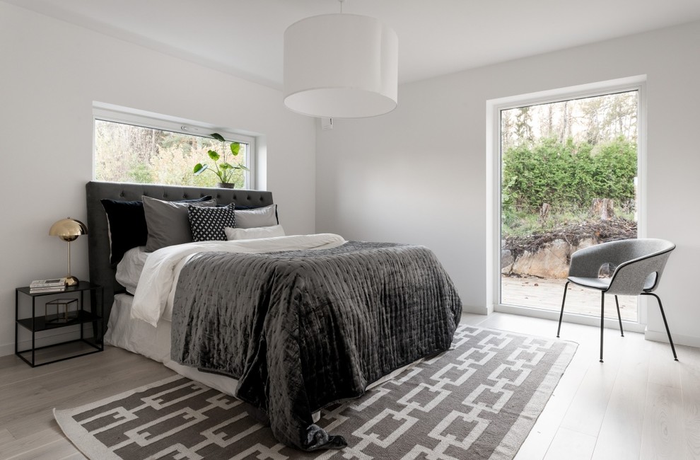 Photo of a mid-sized scandinavian master bedroom in Stockholm with laminate floors, grey floor and white walls.