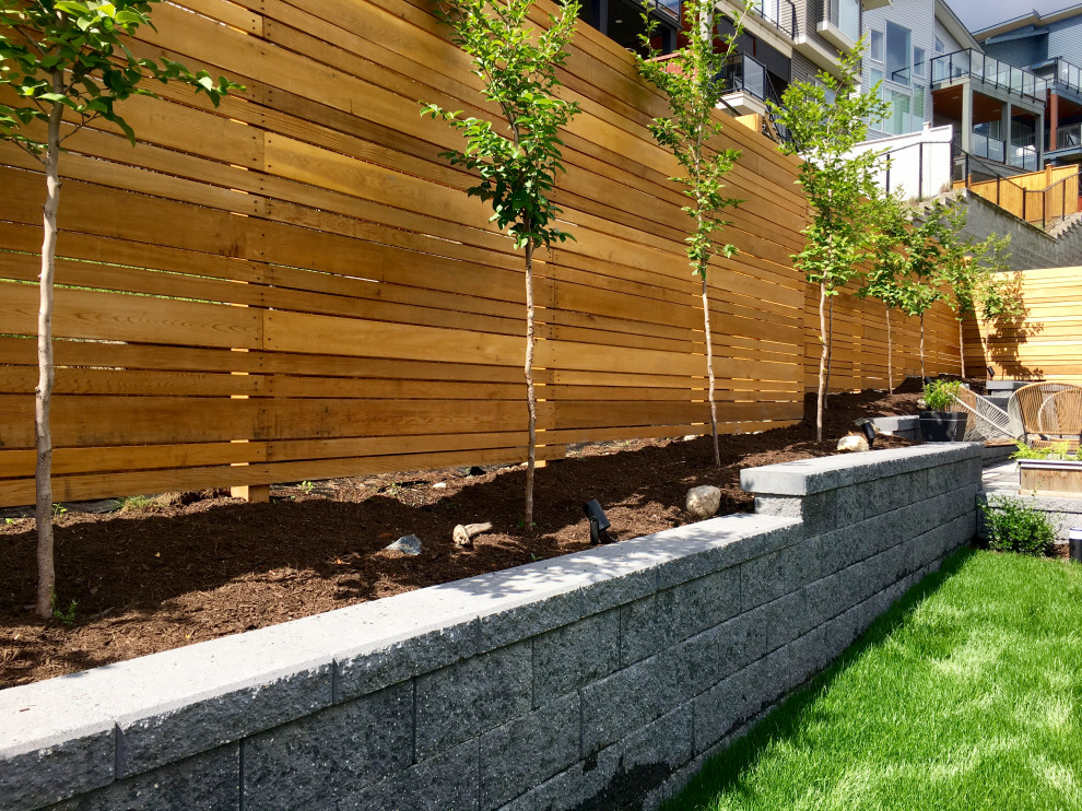 Foto di un giardino minimalista esposto in pieno sole di medie dimensioni in primavera con recinzione in legno, un pendio, una collina o una riva e un muro di contenimento