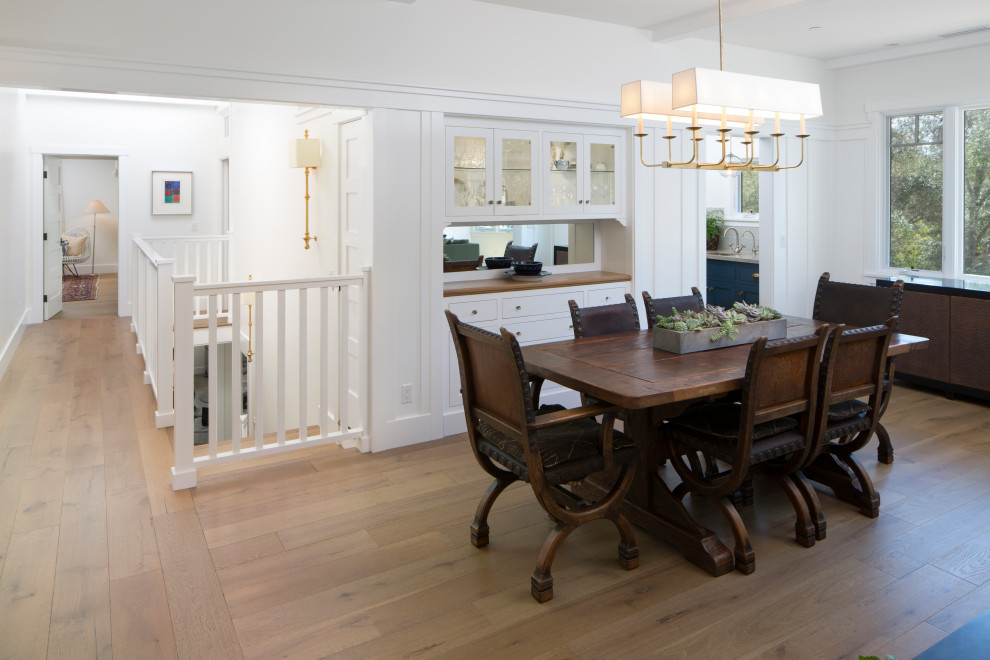 Immagine di una sala da pranzo american style con pareti bianche, pavimento in legno massello medio, pavimento marrone e travi a vista