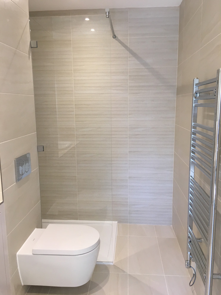 This is an example of a small traditional master bathroom in London with flat-panel cabinets, beige cabinets, an open shower, a wall-mount toilet, beige tile, porcelain tile, beige walls, porcelain floors, a drop-in sink, tile benchtops, beige floor and beige benchtops.