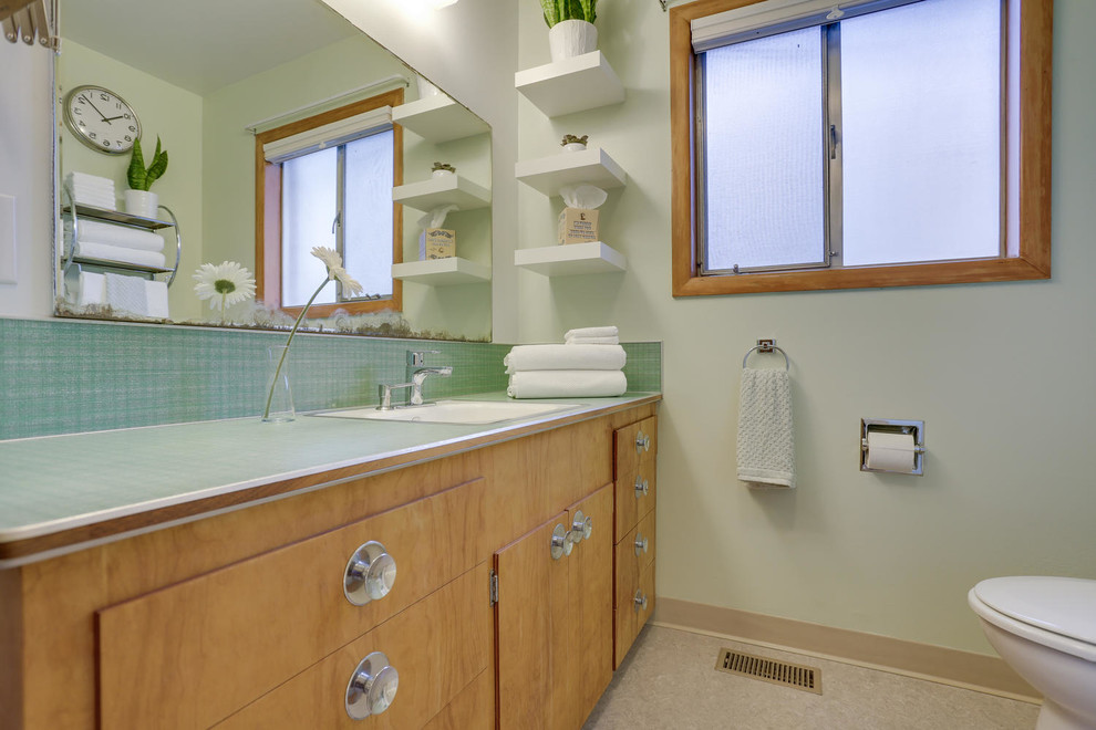 Photo of a mid-sized midcentury master bathroom in Portland with flat-panel cabinets, medium wood cabinets, an alcove tub, a shower/bathtub combo, a two-piece toilet, gray tile, ceramic tile, green walls, linoleum floors, a drop-in sink, laminate benchtops, green floor and a shower curtain.