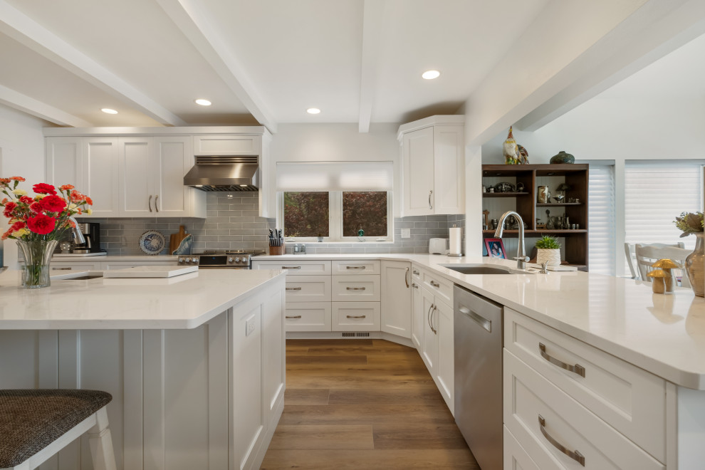 This is an example of a medium sized coastal galley kitchen/diner in Seattle with a built-in sink, beaded cabinets, white cabinets, marble worktops, grey splashback, ceramic splashback, stainless steel appliances, vinyl flooring, multiple islands, brown floors, white worktops and a coffered ceiling.