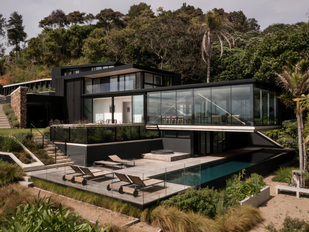 Large and black modern house exterior in Auckland with four floors and wood cladding.