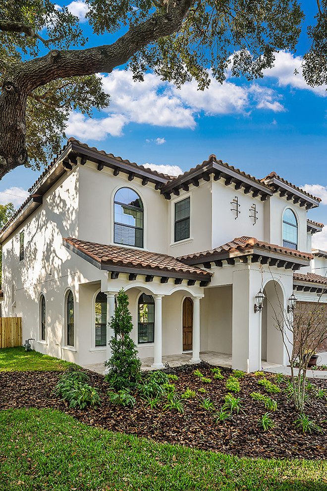 Large mediterranean two-storey stucco white house exterior in Tampa with a hip roof and a tile roof.