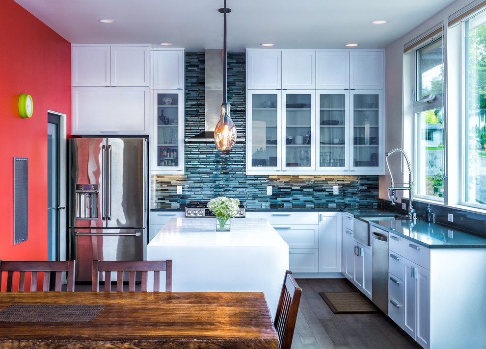 This is an example of a contemporary l-shaped open plan kitchen in Seattle with glass-front cabinets, white cabinets, blue splashback, with island, a farmhouse sink, mosaic tile splashback, stainless steel appliances and medium hardwood floors.
