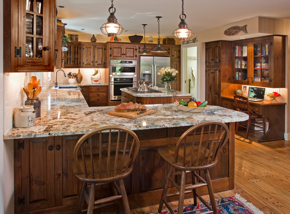 This is an example of a mid-sized traditional l-shaped kitchen in Philadelphia with medium wood cabinets, granite benchtops, stainless steel appliances, medium hardwood floors, with island, an undermount sink, raised-panel cabinets and white splashback.