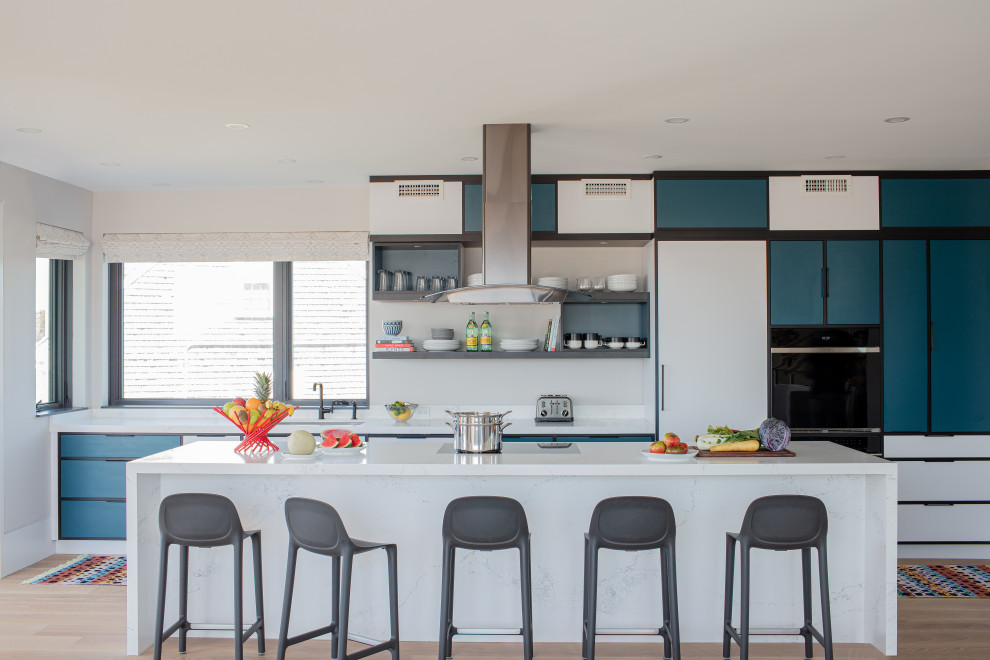 Mid-sized trendy galley light wood floor open concept kitchen photo in Boston with an undermount sink, recessed-panel cabinets, turquoise cabinets, quartz countertops, white backsplash, paneled appliances, an island and white countertops