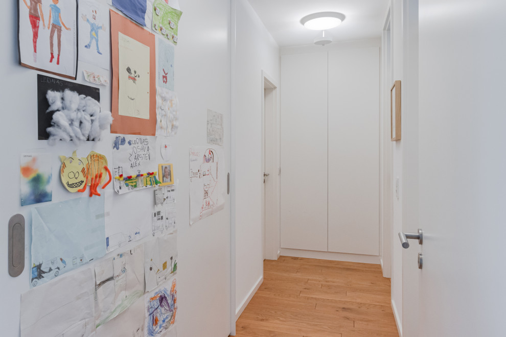 Moderner Flur mit weißer Wandfarbe, braunem Holzboden und braunem Boden in Köln