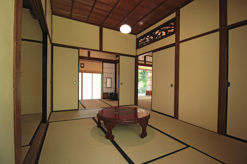 Cette image montre une entrée traditionnelle de taille moyenne avec un mur blanc, un sol de tatami, une porte coulissante, une porte en bois brun, un sol beige et un plafond en bois.