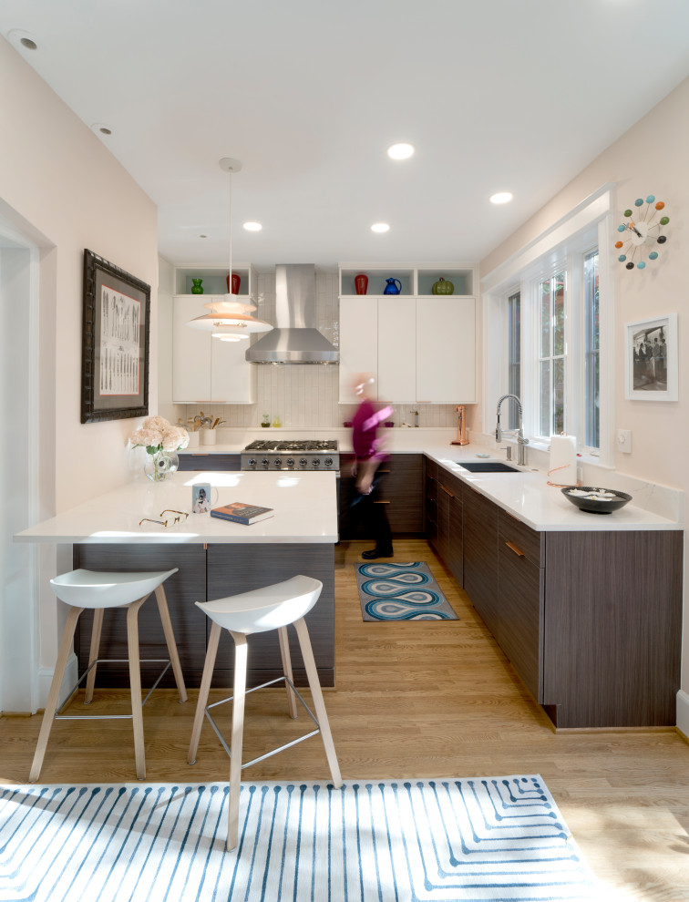 Eat-in kitchen - mid-sized 1960s l-shaped light wood floor and brown floor eat-in kitchen idea in DC Metro with an undermount sink, flat-panel cabinets, dark wood cabinets, quartz countertops, white backsplash, subway tile backsplash, paneled appliances, a peninsula and white countertops