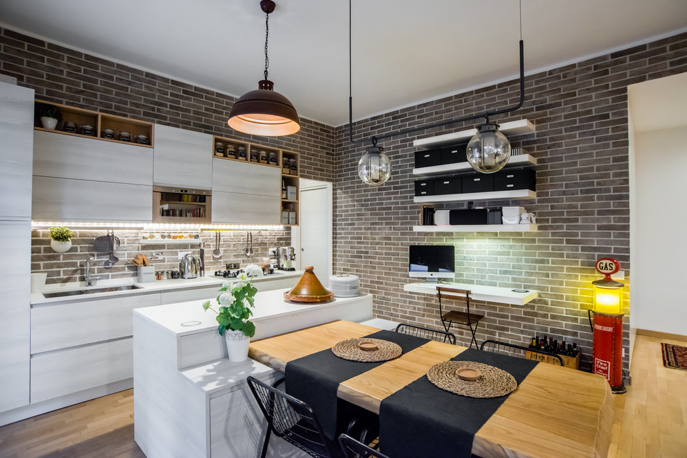Mid-sized industrial single-wall eat-in kitchen in Rome with marble benchtops, stainless steel appliances, with island, an undermount sink, flat-panel cabinets, white cabinets, brick splashback, light hardwood floors and beige floor.