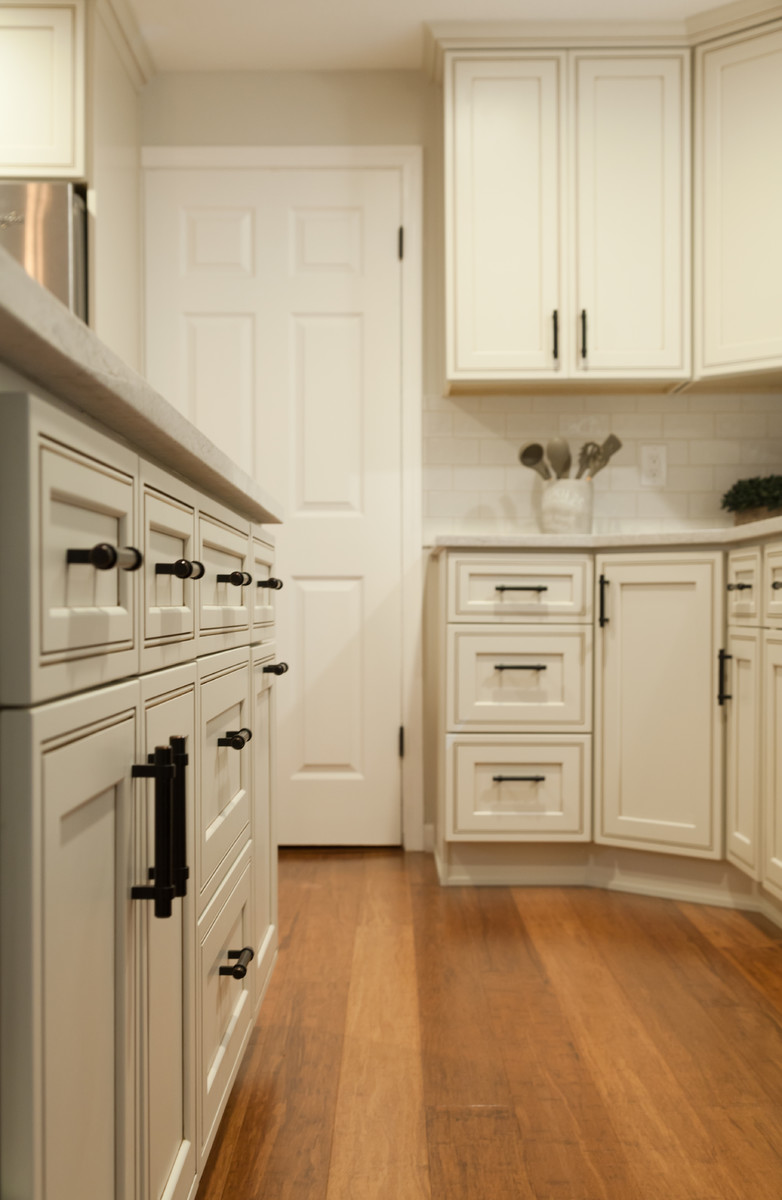 Example of a mid-sized transitional l-shaped bamboo floor and brown floor eat-in kitchen design in Seattle with a double-bowl sink, recessed-panel cabinets, quartz countertops, white backsplash, ceramic backsplash, stainless steel appliances and an island