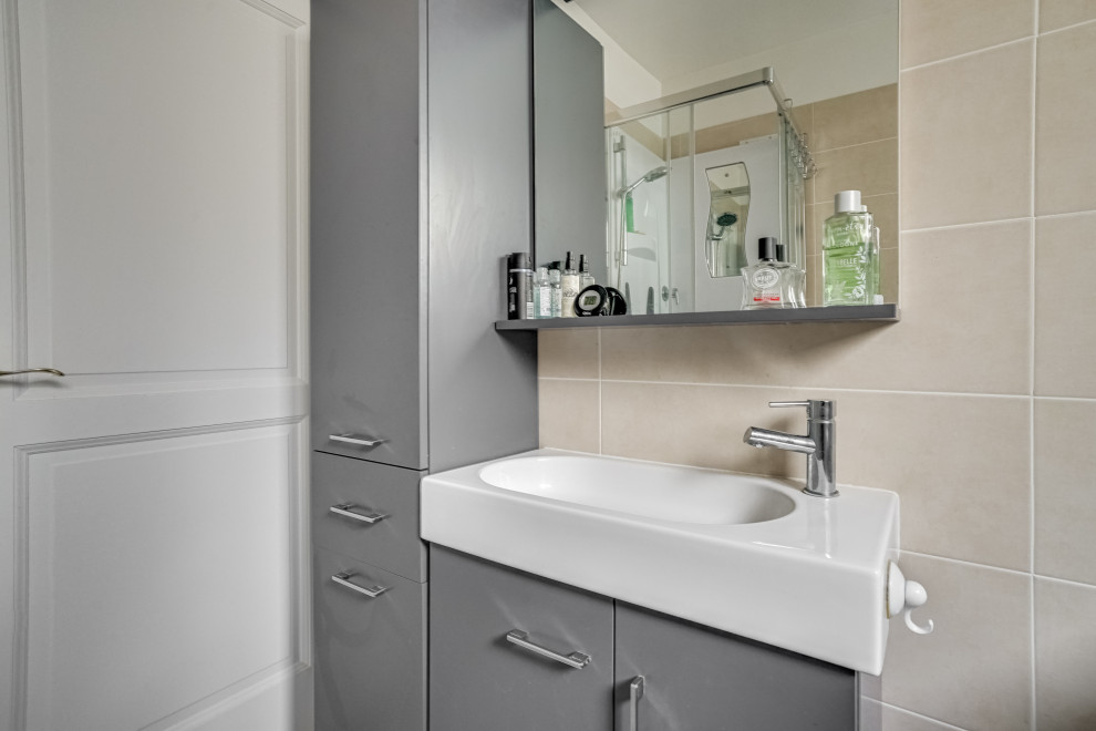 Photo of a small contemporary 3/4 bathroom in Paris with grey cabinets, a corner shower, a one-piece toilet, beige tile, cement tile, beige walls, cement tiles, a trough sink, tile benchtops, grey floor, a sliding shower screen, beige benchtops, a single vanity and a freestanding vanity.
