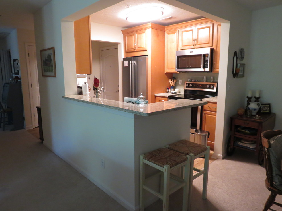 Small transitional galley vinyl floor and brown floor enclosed kitchen photo with an undermount sink, raised-panel cabinets, light wood cabinets, quartz countertops, beige backsplash, glass tile backsplash, stainless steel appliances, no island and beige countertops