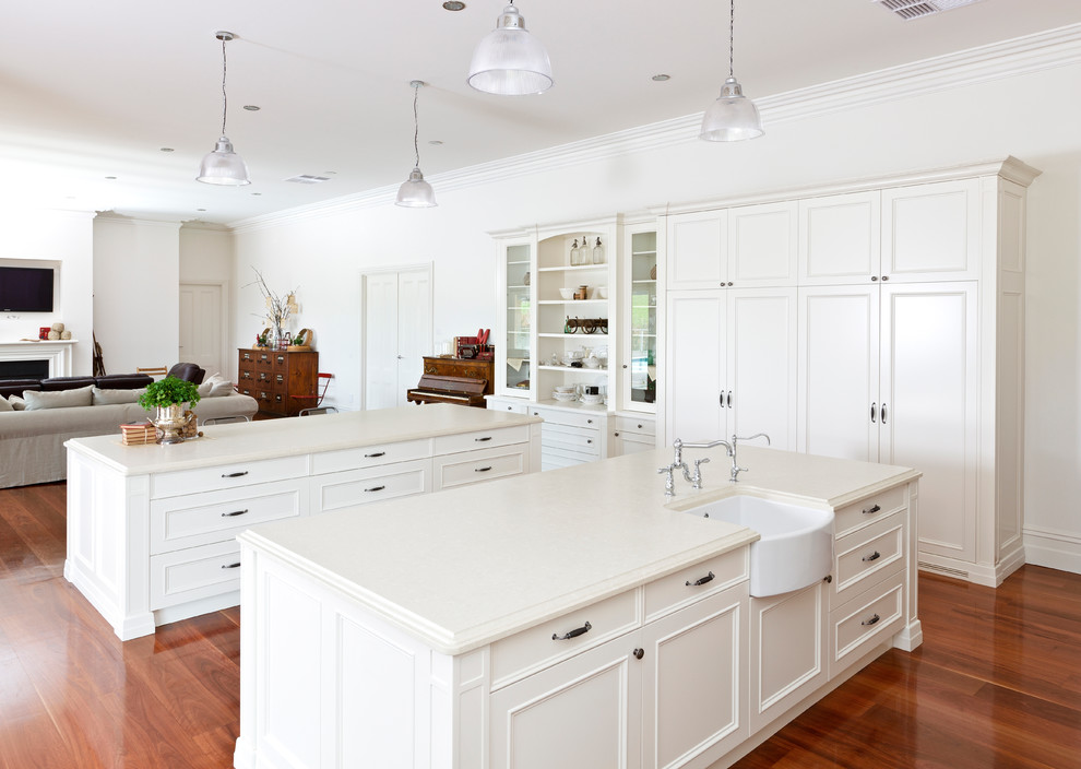Photo of a transitional eat-in kitchen in Melbourne with a farmhouse sink, shaker cabinets, white cabinets, black appliances, medium hardwood floors and multiple islands.