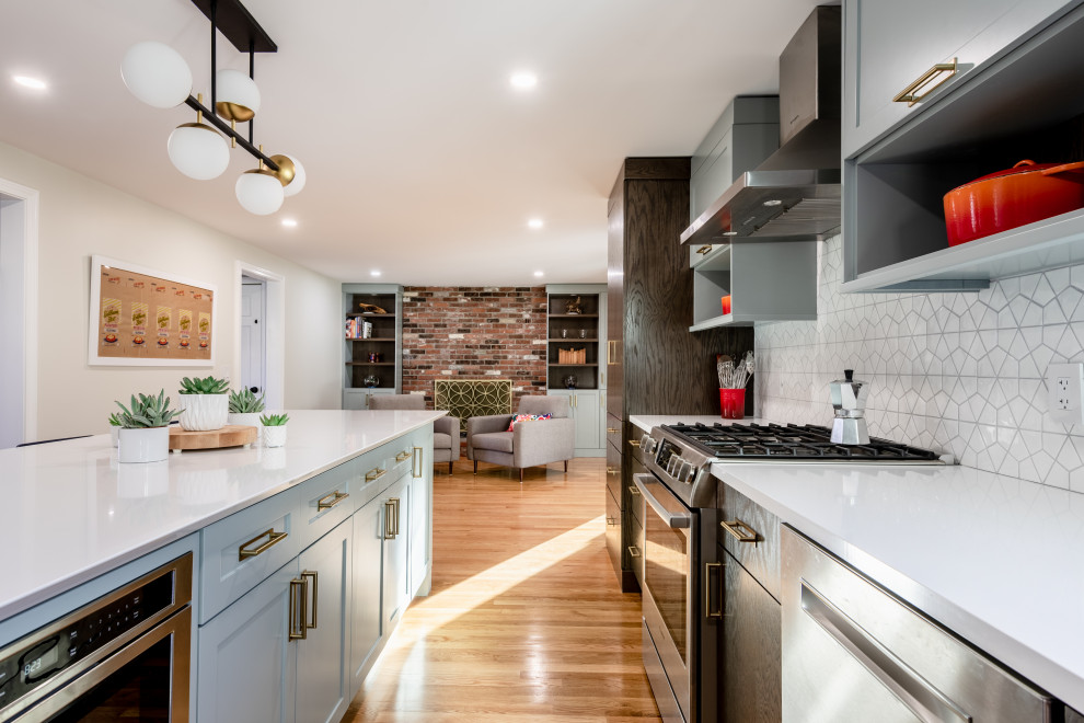 Photo of a mid-sized eclectic l-shaped kitchen in Providence with an undermount sink, recessed-panel cabinets, grey cabinets, white splashback, ceramic splashback, stainless steel appliances, light hardwood floors, with island, brown floor, white benchtop and quartz benchtops.