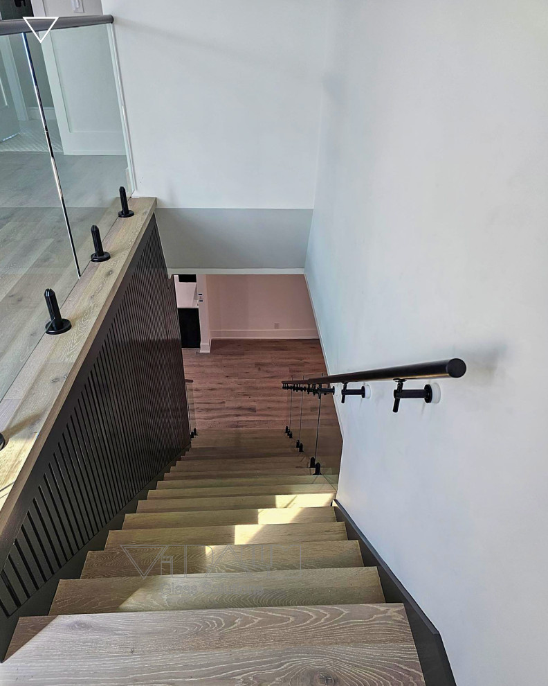 Imagen de escalera recta minimalista grande con escalones de vidrio, barandilla de metal y madera