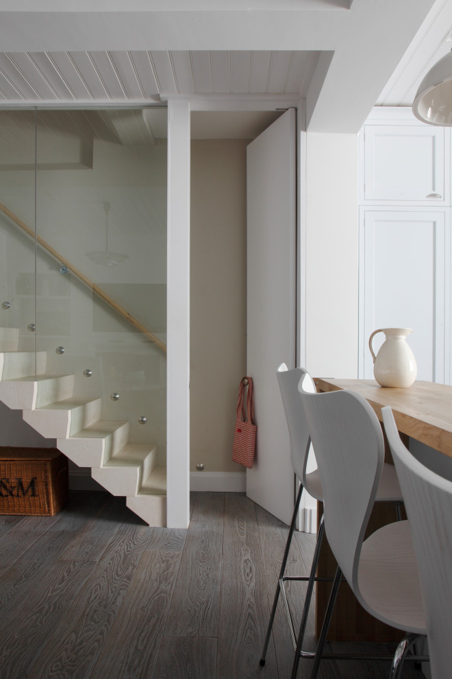 На фото: прямая лестница в современном стиле с ступенями из известняка, подступенками из известняка и стеклянными перилами