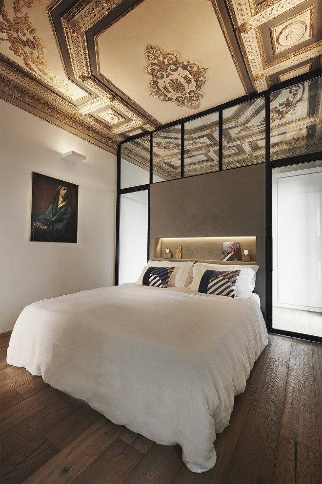 This is an example of a contemporary bedroom in Rome with light hardwood flooring and a coffered ceiling.