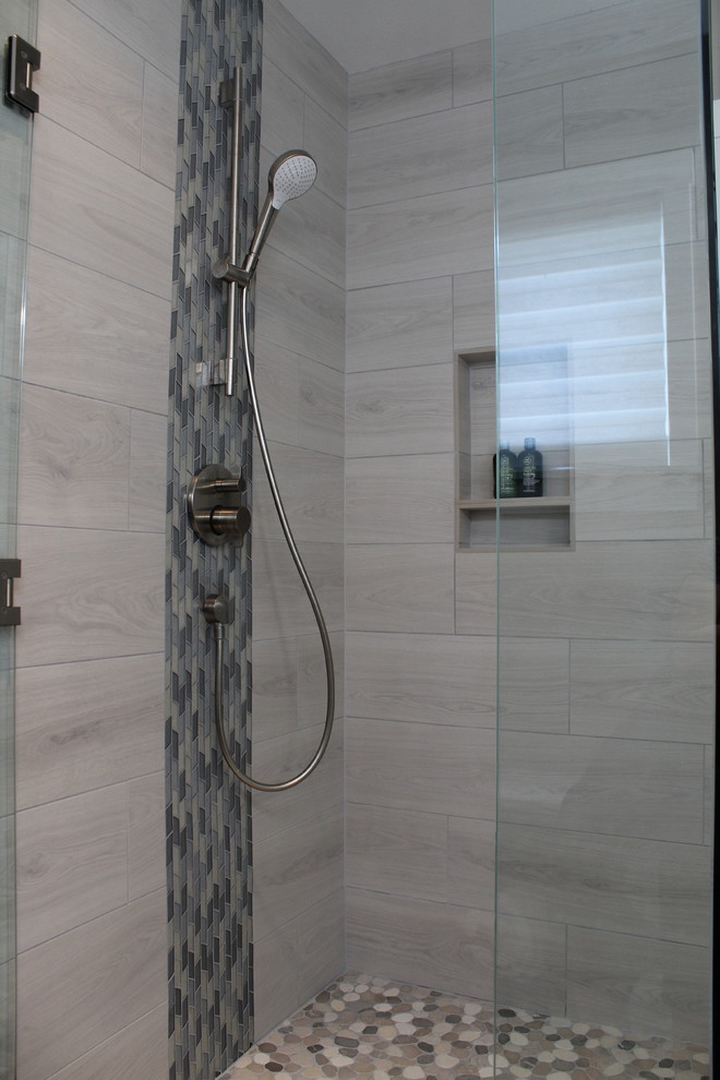 Photo of a mid-sized beach style master bathroom in Seattle with recessed-panel cabinets, blue cabinets, a curbless shower, a two-piece toilet, gray tile, ceramic tile, grey walls, ceramic floors, an undermount sink, engineered quartz benchtops, grey floor, a hinged shower door and multi-coloured benchtops.