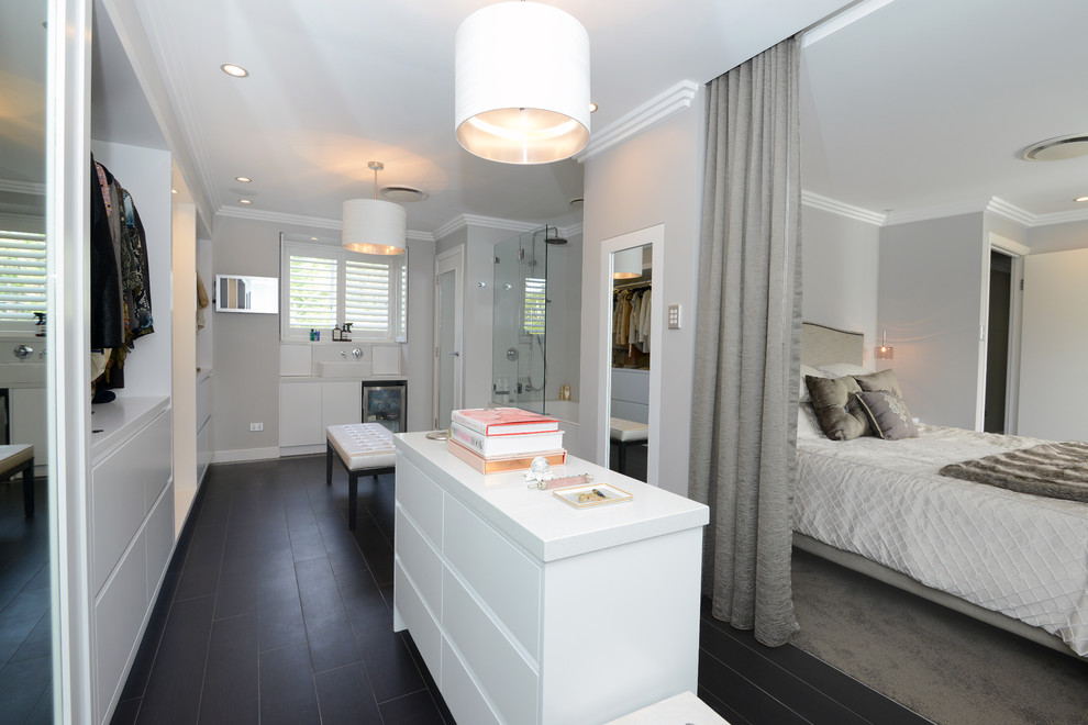 Large contemporary women's walk-in wardrobe in Sydney with white cabinets and porcelain floors.