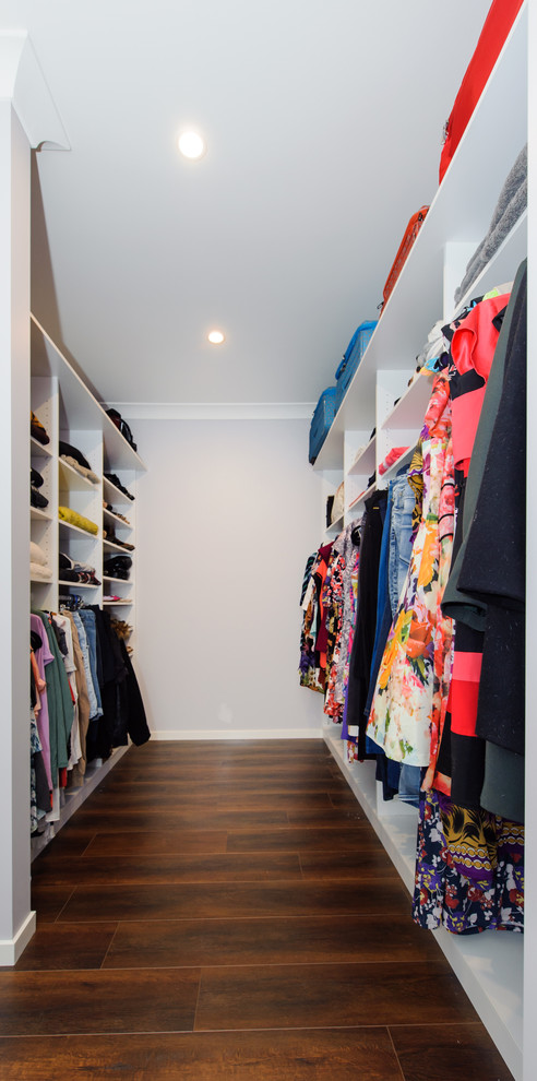 Photo of a small modern gender-neutral dressing room in Sydney with white cabinets, dark hardwood floors and open cabinets.
