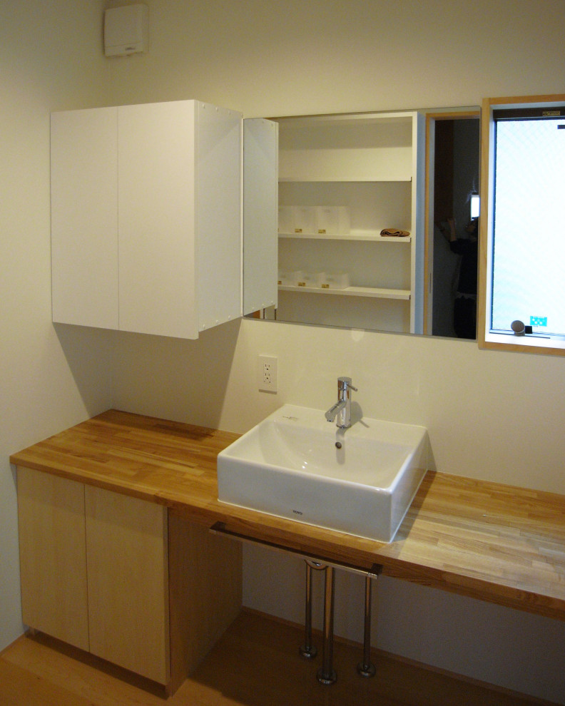 Exempel på ett mellanstort toalett, med vita väggar, ljust trägolv och träbänkskiva