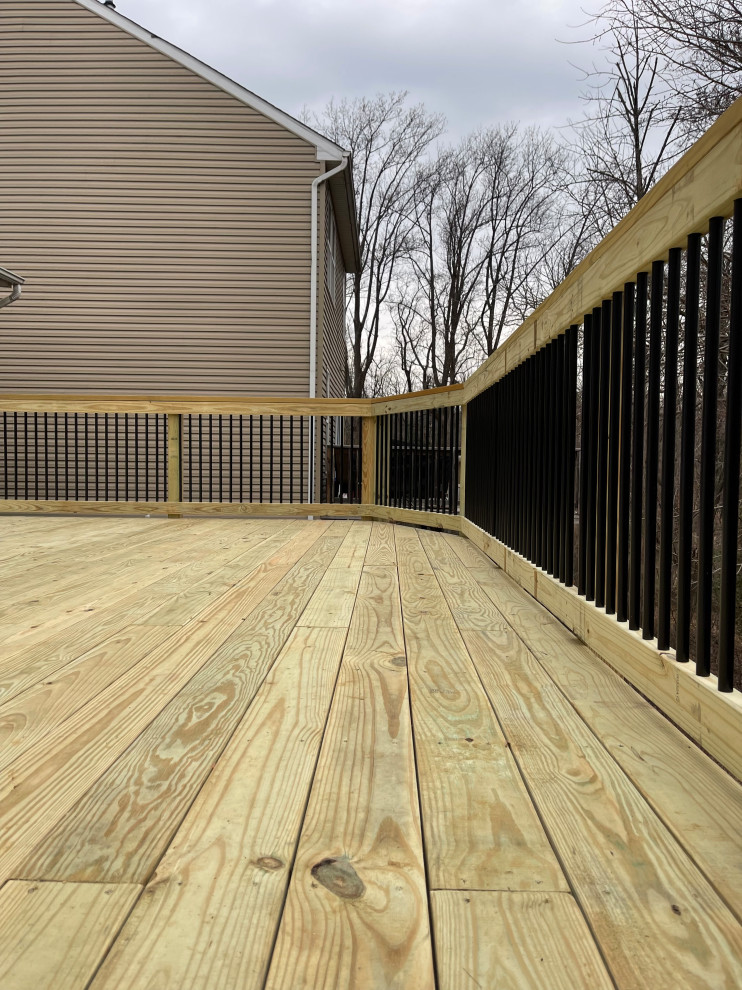 This is an example of a large arts and crafts backyard and first floor deck in Baltimore with mixed railing.