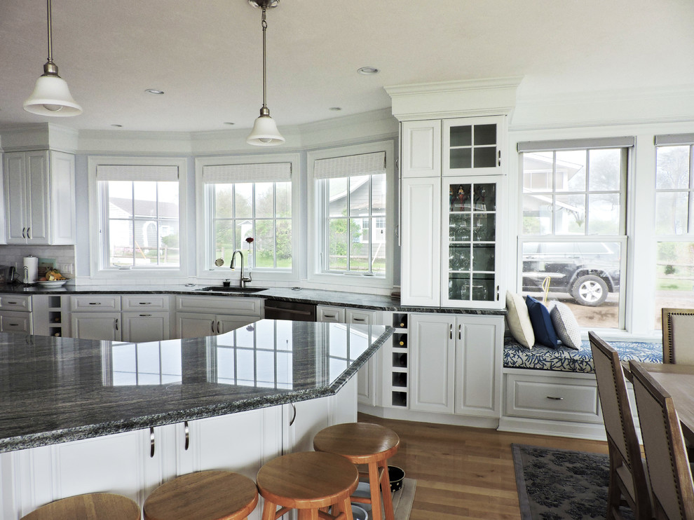 Large beach style u-shaped light wood floor and beige floor eat-in kitchen photo with an undermount sink, raised-panel cabinets, white cabinets, granite countertops, white backsplash, subway tile backsplash, stainless steel appliances, an island and gray countertops