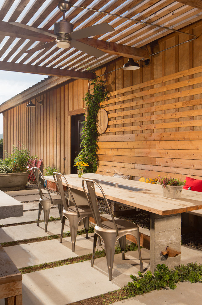 Design ideas for a mid-sized country side yard patio in Seattle with concrete slab and a pergola.