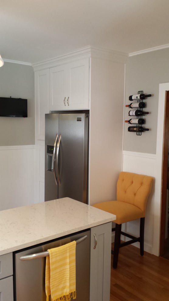 Inspiration for a small transitional u-shaped light wood floor enclosed kitchen remodel in New York with an undermount sink, shaker cabinets, white cabinets, solid surface countertops, gray backsplash, subway tile backsplash, stainless steel appliances and an island