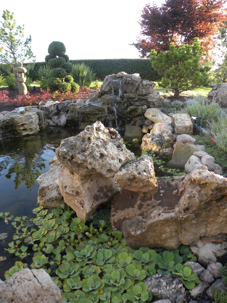 This is an example of a large eclectic backyard partial sun garden for summer in Chicago with with pond.