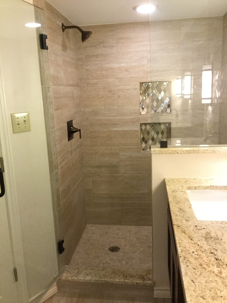 Mid-sized transitional master beige tile and porcelain tile porcelain tile and beige floor drop-in bathtub photo in Dallas with shaker cabinets, medium tone wood cabinets, a two-piece toilet, beige walls, an undermount sink, granite countertops, a hinged shower door and multicolored countertops