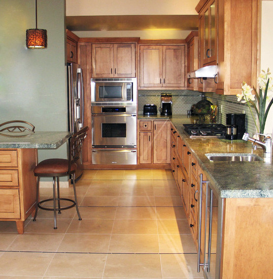 Photo of a large transitional u-shaped kitchen in San Diego with a single-bowl sink, beaded inset cabinets, light wood cabinets, granite benchtops, green splashback, glass tile splashback, stainless steel appliances, limestone floors and with island.