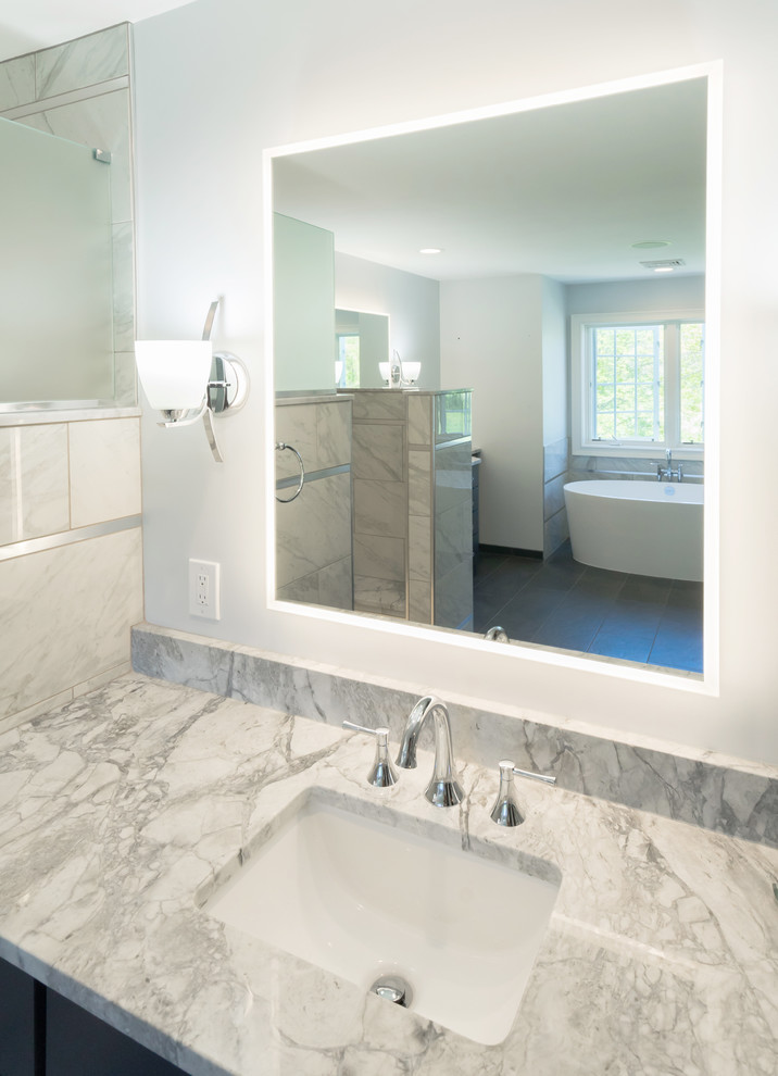 Photo of a large transitional master bathroom in Philadelphia with flat-panel cabinets, blue cabinets, a freestanding tub, an open shower, a two-piece toilet, gray tile, porcelain tile, grey walls, porcelain floors, an undermount sink, granite benchtops, grey floor, an open shower and grey benchtops.
