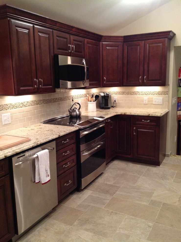 Transitional u-shaped kitchen photo in Boston with dark wood cabinets, granite countertops, beige backsplash, ceramic backsplash and stainless steel appliances