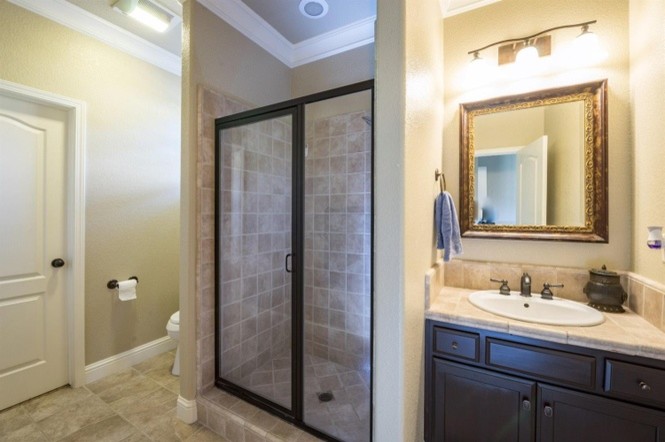 Design ideas for a mid-sized contemporary 3/4 bathroom in Other with raised-panel cabinets, dark wood cabinets, gray tile, ceramic tile, ceramic floors, an undermount sink, tile benchtops, an alcove shower, a two-piece toilet, beige walls, beige floor and a hinged shower door.