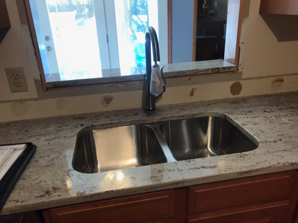 Mid-sized l-shaped light wood floor and brown floor open concept kitchen photo with a double-bowl sink, raised-panel cabinets, medium tone wood cabinets, granite countertops, stainless steel appliances, no island and white countertops