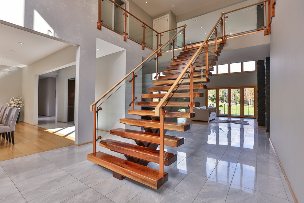 Large contemporary wood straight staircase in New York with open risers and glass railing.