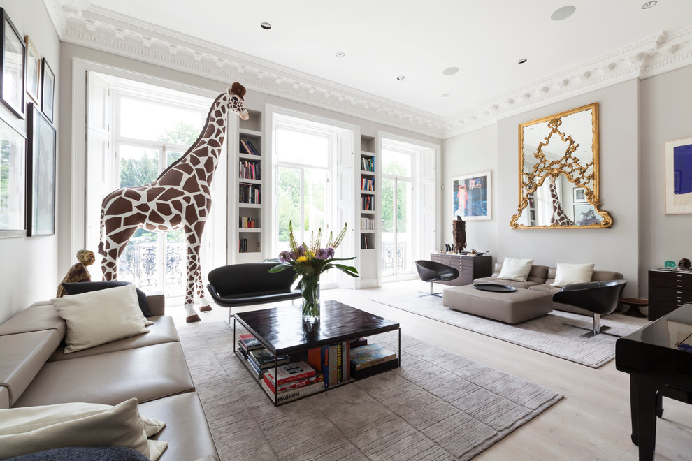 Photo of a large eclectic formal open concept living room in London with grey walls and light hardwood floors.