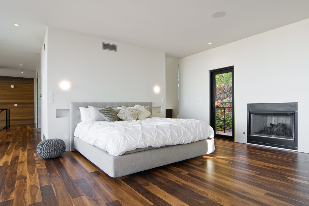 Inspiration for a modern bedroom in Salt Lake City with white walls, dark hardwood floors and a standard fireplace.