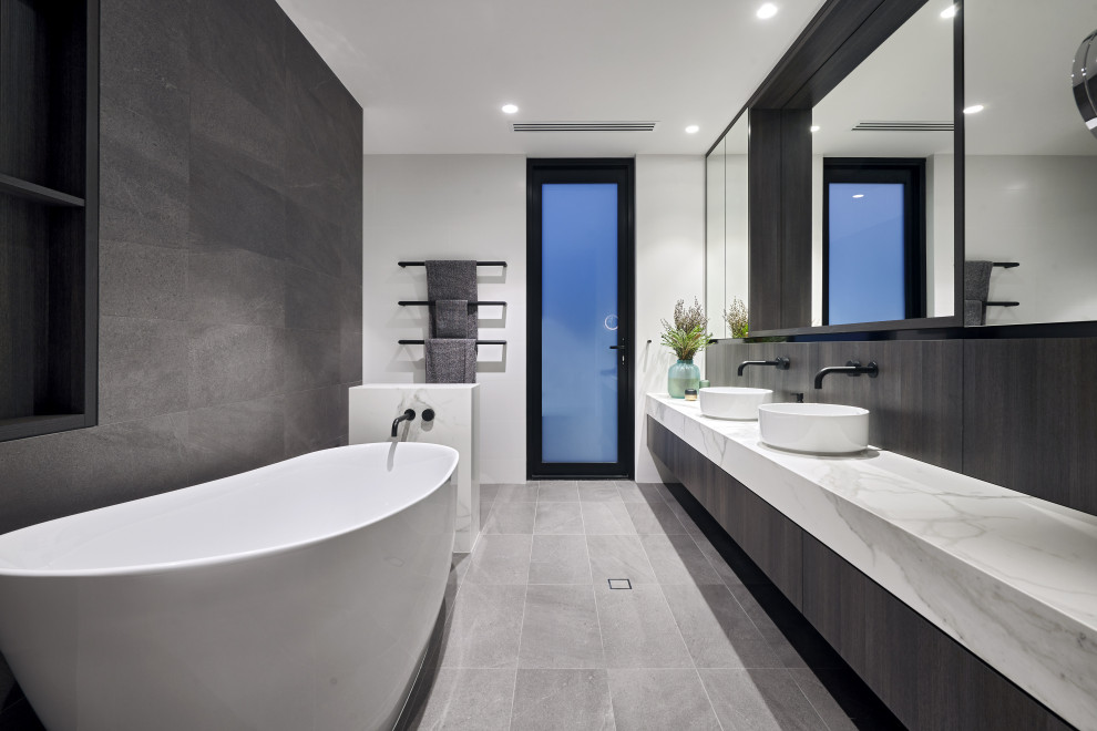 Contemporary master bathroom in Perth with a freestanding tub, gray tile, marble benchtops, a double vanity, flat-panel cabinets, grey cabinets, white walls, a vessel sink, grey floor, white benchtops and a floating vanity.