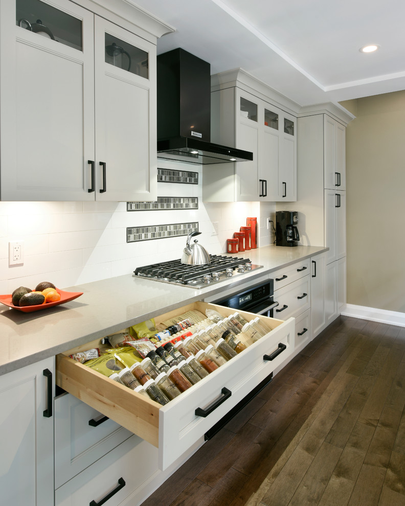 Transitional single-wall medium tone wood floor and brown floor open concept kitchen photo in Ottawa with a double-bowl sink, shaker cabinets, white cabinets, white backsplash, subway tile backsplash, black appliances and an island