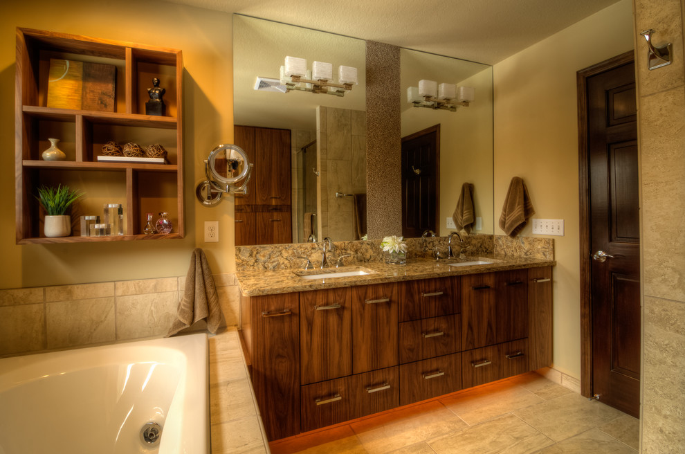 Photo of a mid-sized contemporary master bathroom in Minneapolis with flat-panel cabinets, dark wood cabinets, a drop-in tub, an alcove shower, a one-piece toilet, beige tile, ceramic tile, beige walls, ceramic floors, an undermount sink, granite benchtops, beige floor and a hinged shower door.
