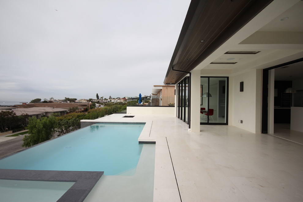 This is an example of a mid-sized contemporary backyard rectangular infinity pool in Orange County with a hot tub and tile.